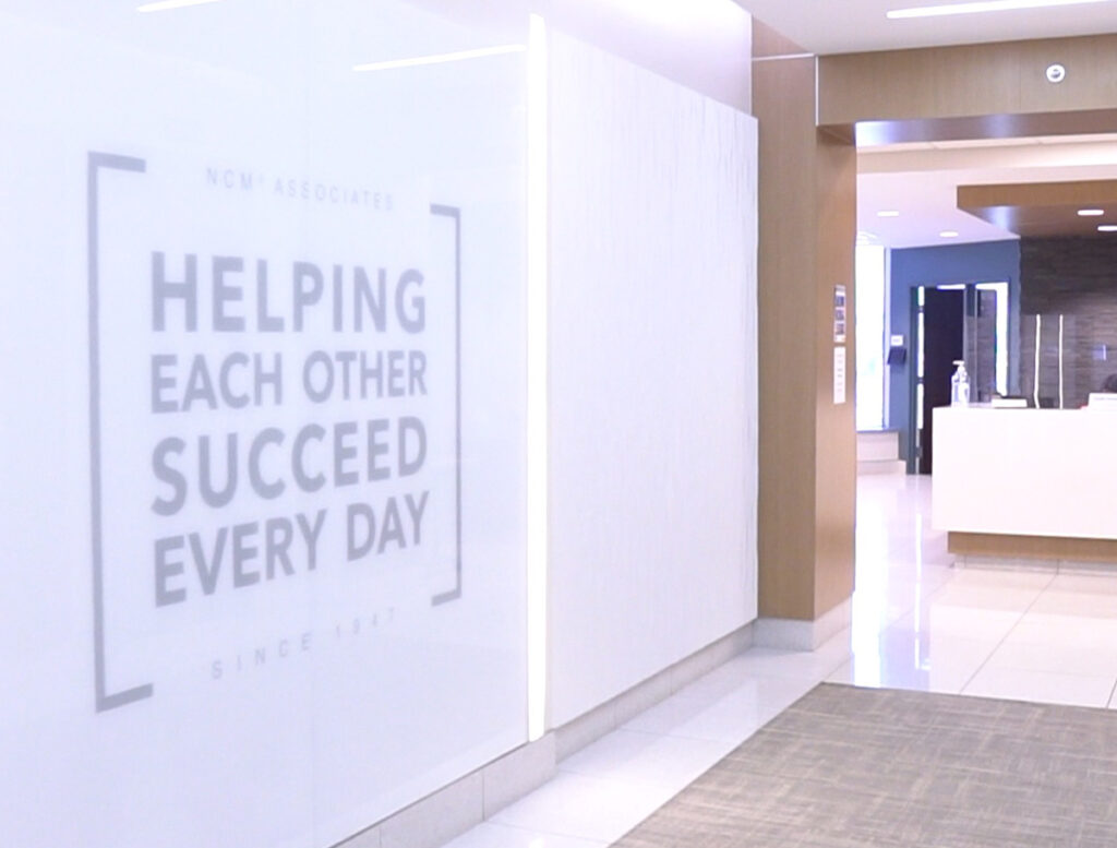a view of the NCM lobby. text on the wall reads "Helping each other succeed every day."