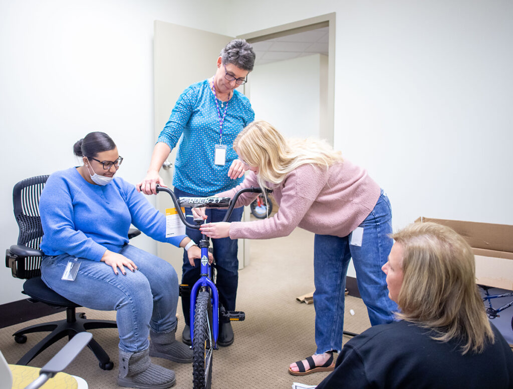 3 adult women are examining a bicycle