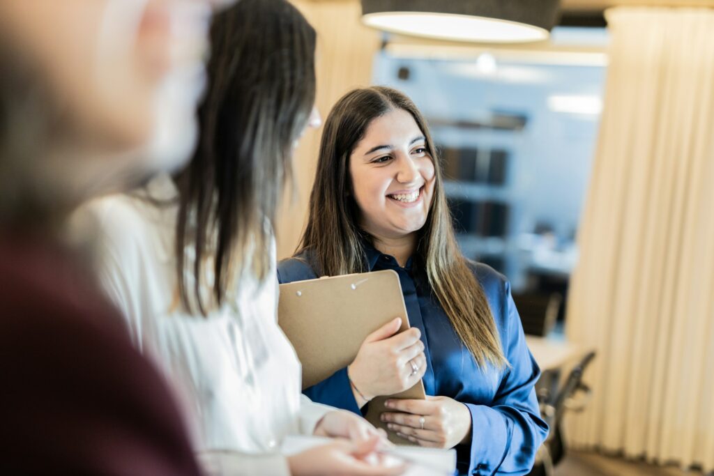 a close up of two women smiling in a conference room setting