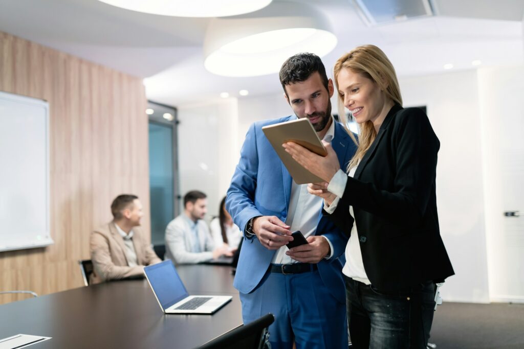 a man and a woman look at a tablet she is holding between them