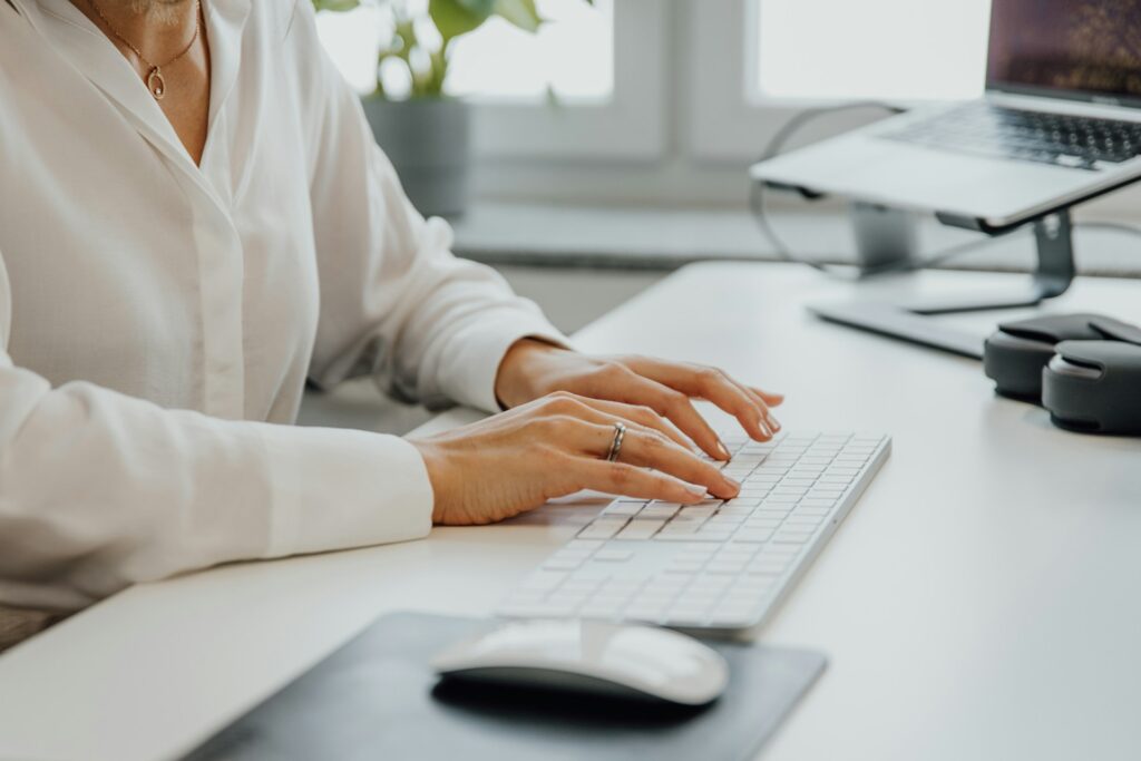 a close up of a woman's hands while she works at a desk top computer in an office setting