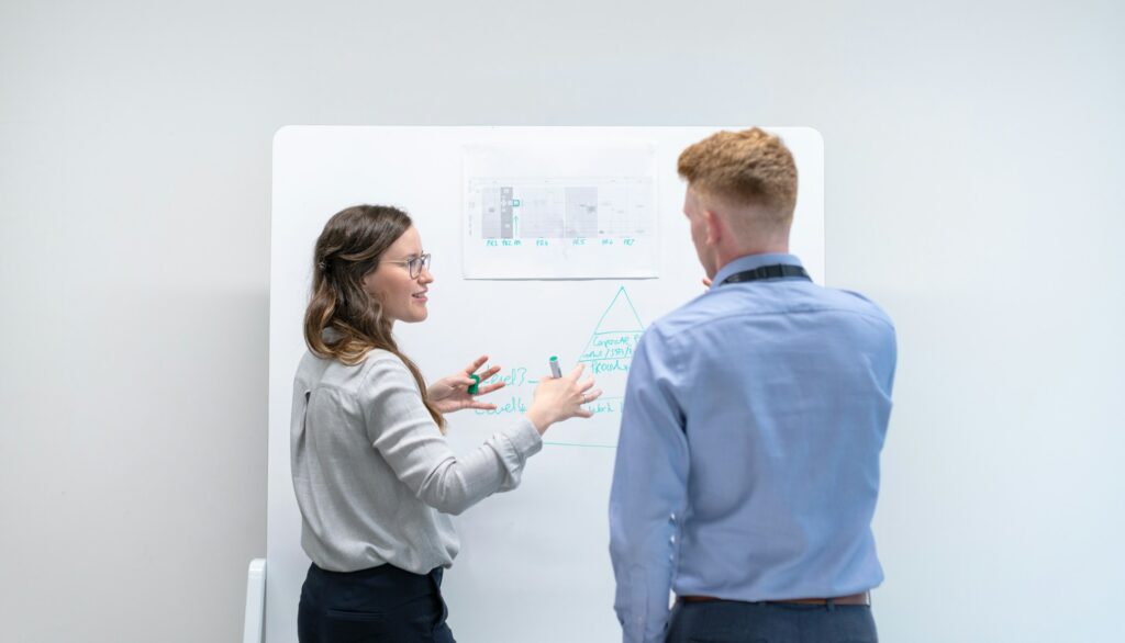a man and woman discuss a notes written on a white board