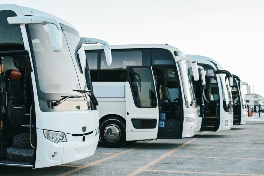 several motorcoaches lined up on in a parking lot.