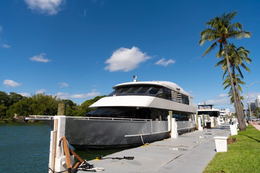 a double-decker yacht is tied up on a pier underneath a blue sky.