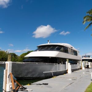 a double-decker yacht is tied up on a pier underneath a blue sky.
