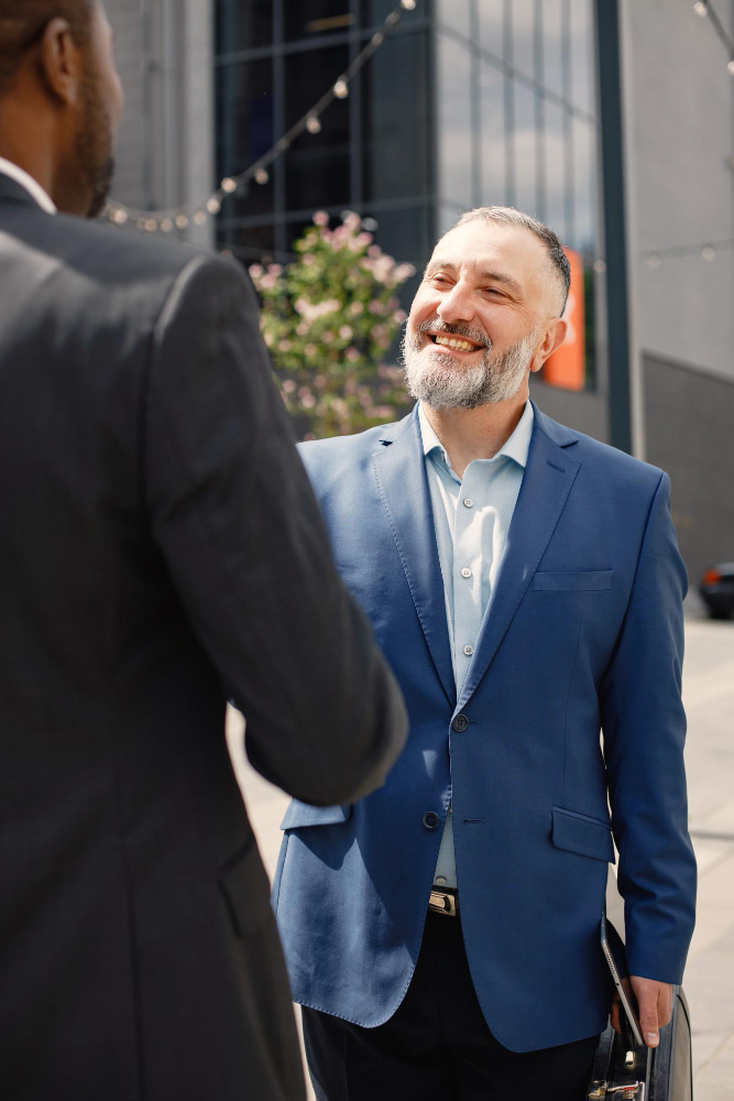 two men are shaking hands in an outdoor, urban setting.