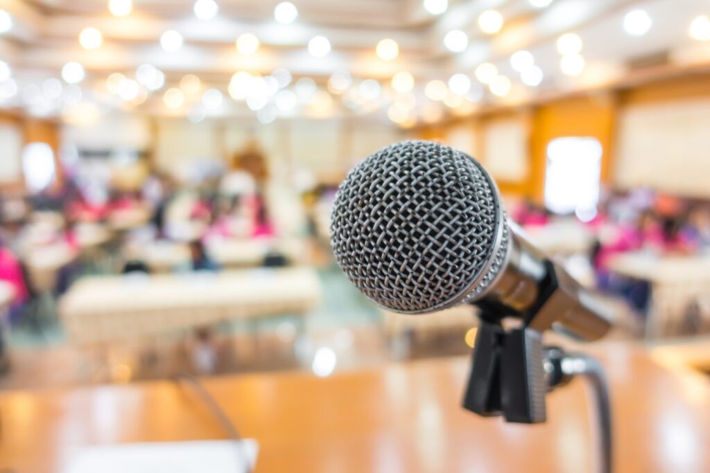 a close up photo focused on a microphone in front of a blurred out classroom background