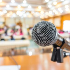 a close up photo focused on a microphone in front of a blurred out classroom background