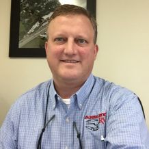 Bill Ansley is wearing a blue collared shirt and smiling at the camera.