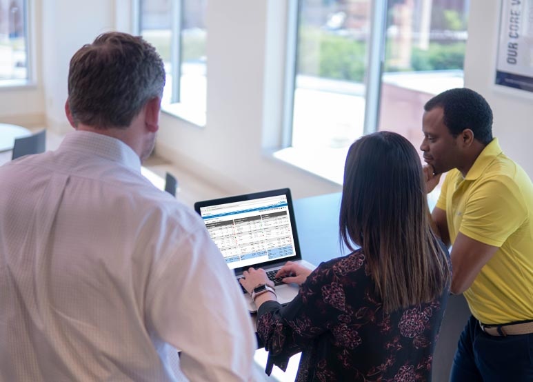 a group of three people are gathered around a laptop with an axcessa dashboard displayed