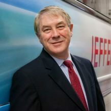 Steve Woelfel is smiling and facing the camera, wearing a suit and tie.