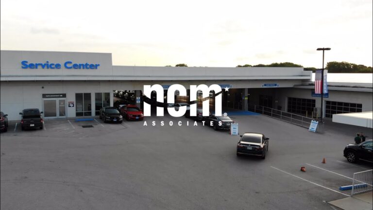 the NCM Associates logo imposed over the image of the parking lot and garage at a Ford service center