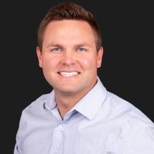 a headshot for Tyler Pederson, brown hair and a collared shirt, smiling